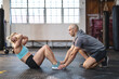 © Wavebreak Media - Caucasian male trainer instructing woman exercising at gym, doing sit ups