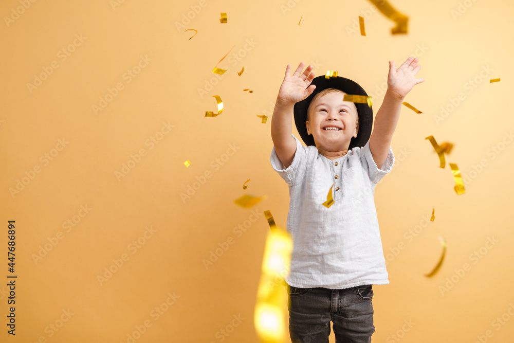 White boy with down syndrome in hat playing with confetti - obrazy, fototapety, plakaty 