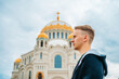 A young man walks on the square with the Sea Cathedral in Kronstadt, Russia