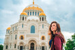 Young beautiful woman walks on the square with the Sea Cathedral in Kronstadt, Russia