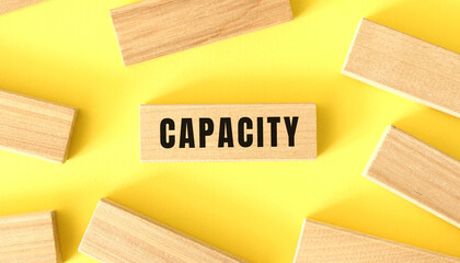 The word CAPACITY is written on a wooden blocks on a yellow background.