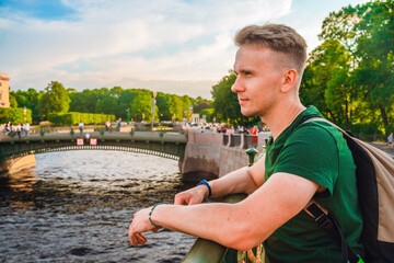 Wall Mural - A young man walks along the embankment in the center of St. Petersburg in the summer