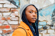 Italy, Milan, Portrait Of Woman With Braids Against Brick Wall