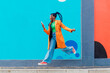 © Image Source RF - Italy, Milan, Woman with braids jumping against blue wall