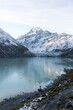 © Travel 'n' Lifestyle - Travel lifestyle view of person stood at frozen alpine Hooker Lake, with reflection of Mount Cook mountain, during winter in Mount Cook National Park, on the south island of New Zealand.