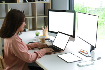 female programmer working with laptop, two computers and tablet, blank screen of devices, programmer