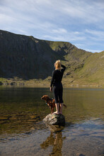 Travel Lifestyle View Of Girl And Adventure Dog Hiking By Red Tarn Lake Near Helvellyn Mountain Peak In Lake District National Park, England, UK.
