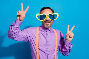 Poster - Photo of mature man happy positive smile show peace cool v-sign wear sunglass isolated over blue color background