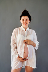 Wall Mural - beautiful pregnant girl in a shirt with a bare stomach.