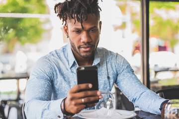 Young man using his mobile phone at a restaurant.