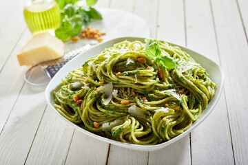 Wall Mural - Portion of delicious pesto pasta with cheese on the kitchen table