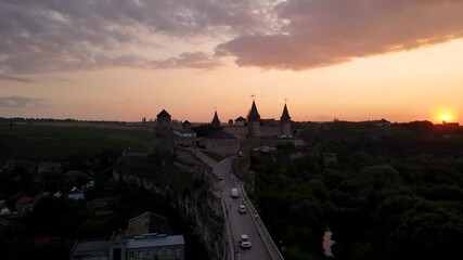 Wall Mural - Aerial drone view of medieval castle at sunset in Kamianets-Podilskyi town