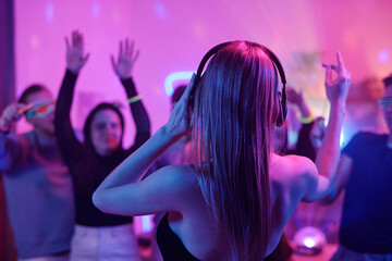 Sticker - Back view of young woman with long blond hair touching headphones