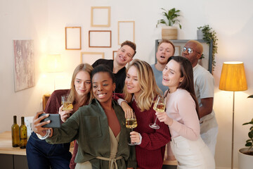 Wall Mural - Group of happy young intercultural friends in smart casualwear making selfie