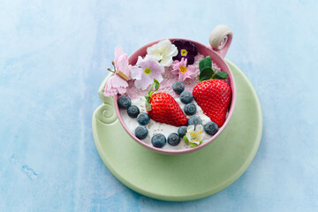 Poster - Green cup of ice cream with strawberries and blackberries on the blue background