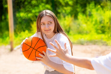 beautiful teenage girls with long hair holds a basketball ball, plays streetball outside