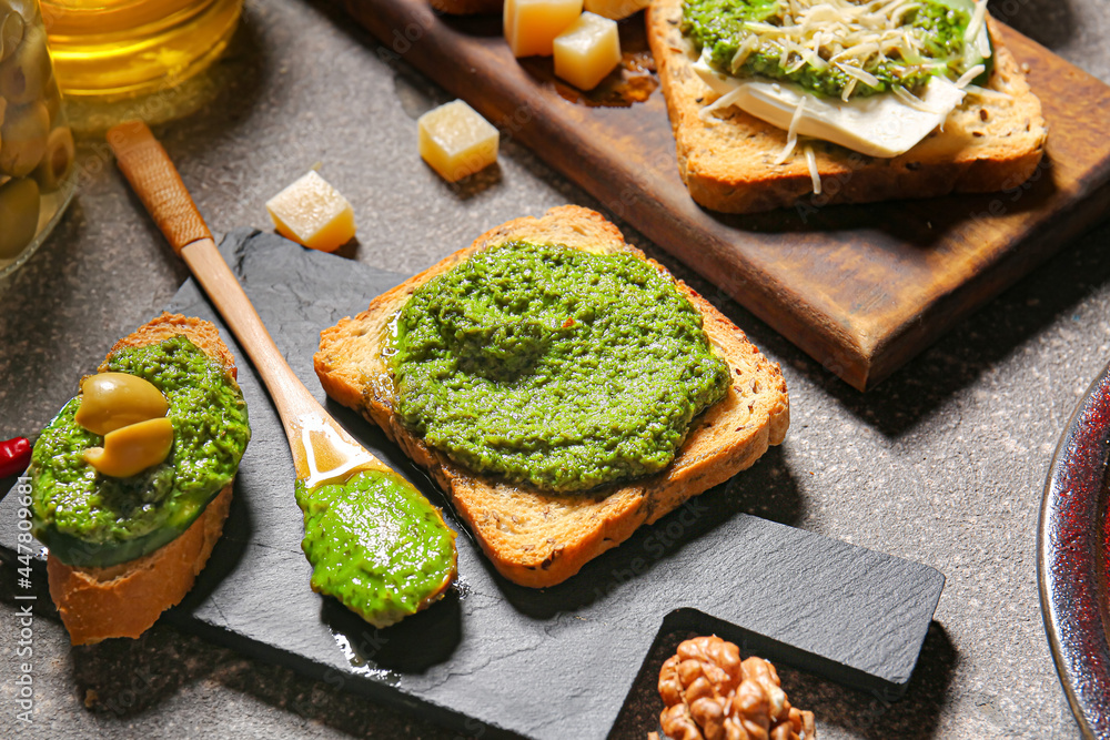 Tasty toasts with pesto sauce on grunge background, closeup