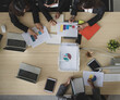 © Bangkok Click Studio - Bird eye view of group of four attractive Asian female office worker colleagues in formal business suits working together on charts and graphs in office with computer desktop and laptop on the table