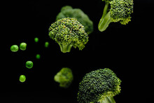 Flying Green Peas And Broccoli On Dark Background