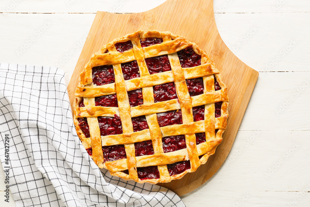 Board with tasty cherry pie on light wooden background