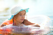 © Ольга Симонова - Girl in a hat swimming in the river with a transparent inflatable circle in the shape of a heart with orange feathers inside.The sea with a sandy bottom. Beach holidays, swimming, tanning, sunscreens.