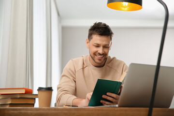 Canvas Print - Man reading book at table in library