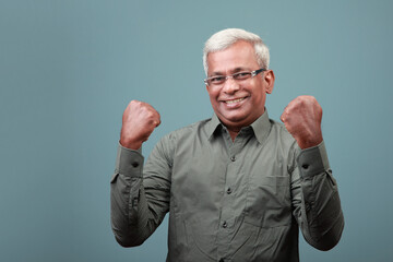 A cheering man of Indian ethnicity raises his fists