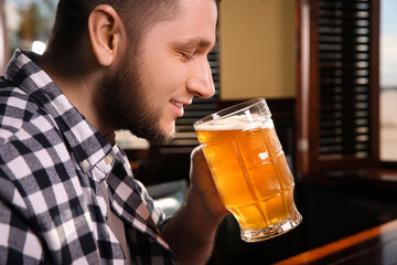 Canvas Print - Man drinking tasty beer in pub, closeup