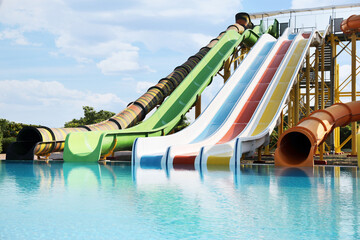 Wall Mural - Beautiful view of water park with colorful slides and swimming pool on sunny day