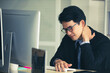 © Bangkok Click Studio - Asian young black short hair male employee worker wears formal suit with necktie gray shirt and eyeglasses has office syndrome hurt shoulder and neck when working in front computer monitor at table