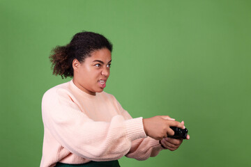 Beautiful african american woman on green background focused playing video games