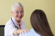 © Bangkok Click Studio - Senior older female doctor taking, explaining and history taking with a patient with a smiley face and intimate manner. She touches the shoulder's patient with a kind gesture.