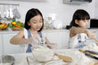 © Bangkok Click Studio - Two little cute long black fair hair Asian girl, 3 years and 7 years old, learning how to make bread and bakery with a curious and happy smile face. She learns and plays with flour in a bowl