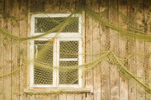 Fishermen's Nets Are Hung By The Window Of A Wooden House.