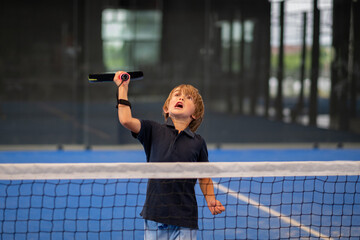 Monitor teaching padel class to child, his student - Trainer teaches little boy how to play padel on indoor tennis court