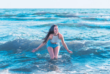 Young woman playing in the sea.woman make in sea water splash.Cheerful young woman having fun on the summer beach.