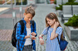Little girl and kid boy using ther smart watch near school