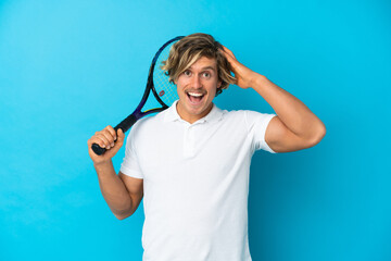 blonde tennis player man isolated on blue background with surprise expression