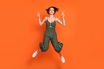 Full length photo of young girl happy positive smile show peace cool v-sign isolated over orange color background