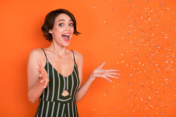 Photo of young girl happy positive smile amazed shocked surprise air fly confetti party isolated over orange color background