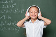 © LIGHTFIELD STUDIOS - joyful schoolgirl with closed eyes listening music in headphones near chalkboard