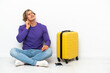 © luismolinero - Young blonde man with suitcase sitting on the floor thinking an idea