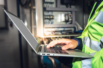 Engineer man using computer notebook for Checking the electrical system Of the machine in the industrial factory, to engineering and industry concept.