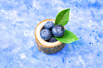 Wall Mural - Hand made stump bowl with blueberries on a blue background