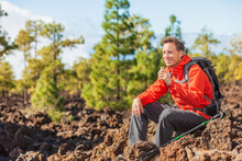 Hiking Man Eating Granola Protein Bar Snack During Mountain Hike Travel Camping Vacation In Nature Landscape. Happy Hiker Taking A Break With Healthy Food In His Backpack.