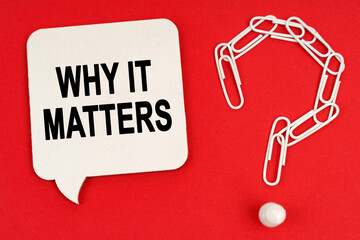 On a red background are a question mark made of paper clips and a sign with the inscription - WHY IT MATTERS