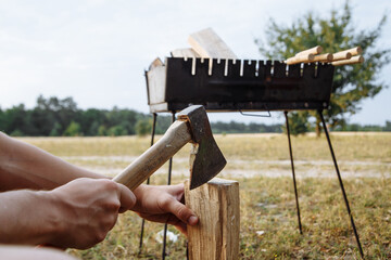 a man in a camping town chops firewood with an ax for a barbecue