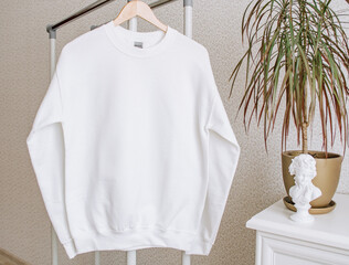 Poster - White sweatshirt mockup on a hanger. Blank hoodie mockup with leaves.
