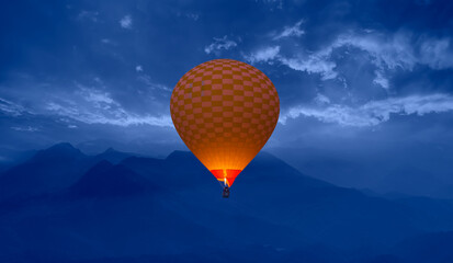 Hot air balloon fly over blue mountains landscape at sunset  
