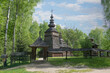 Old village church, built of wood. Picturesque nature, trees, grass. Clouds sky.
